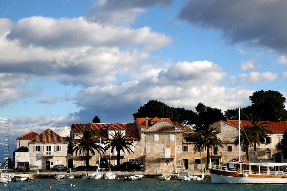 Small fishing boats and traditional Mediterranean houses on promenade in Sutivan, island Brac, Croatia.