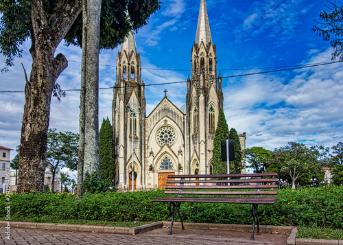 Bench of the square with the church cathedral of Botucatu under blue sky with clouds at dawn in the background photo