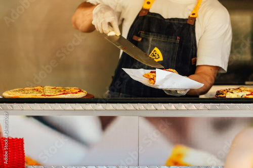 Pizza man serving pizza on a napkin in a food truck