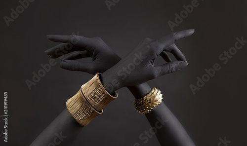 Black woman's hands with gold jewelry. Oriental Bracelets on a black painted hand. Gold Jewelry and luxury accessories