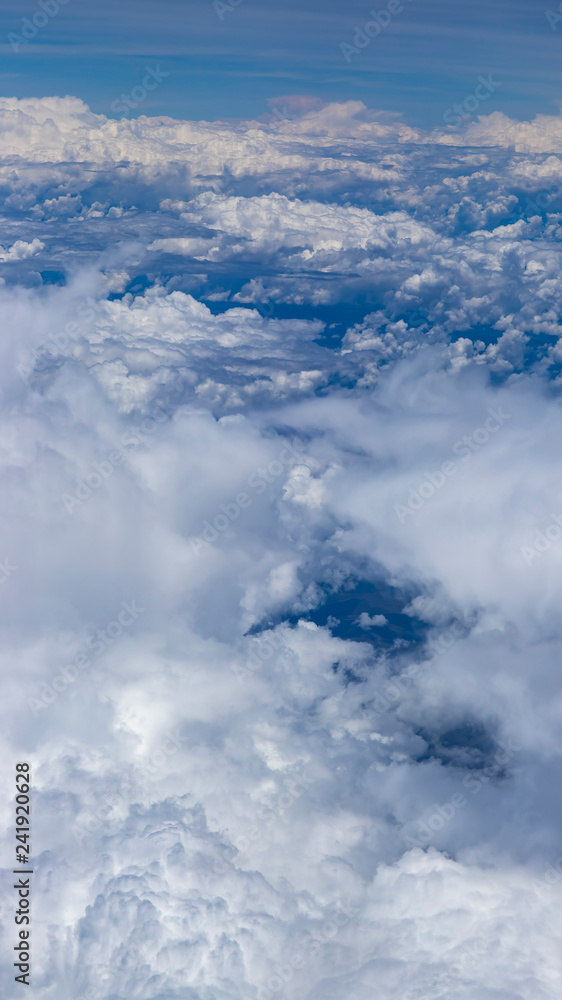 Beautiful view from window of plane flying over clouds. Natural panorama with clouds. White clouds moving above the ground. Beautiful view from window of plane flying over clouds. Natural panorama with clouds. White clouds moving above the ground.