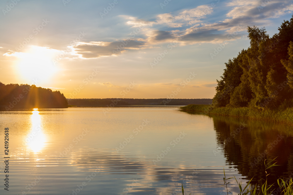 ein See umgeben von Wald bei Sonnenuntergang