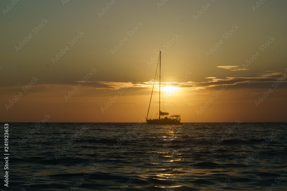 sailboat sailing on the horizon during sunset