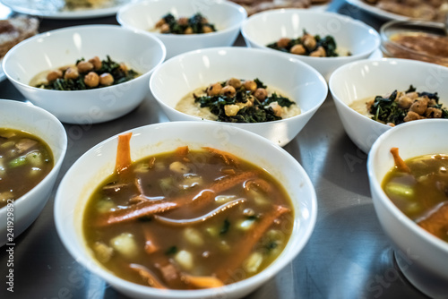 Group of plates with soups of various types in hot bowls.
