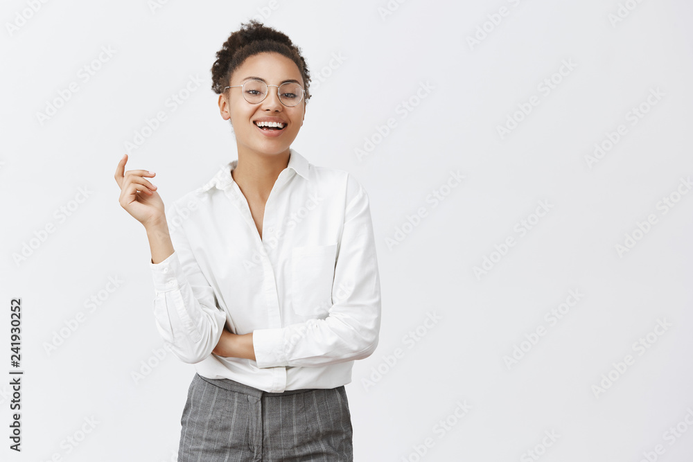 Woman can deal with any customer. Attractive confident and feminine african woman with curly hair, gesturing with raised hand, smiling with self-assured expression, wearing suit and glasses Woman can deal with any customer. Attractive confident and feminine african woman with curly hair, gesturing with raised hand, smiling with self-assured expression, wearing suit and glasses