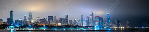 Long panoramic view of Chicago skyline at night with top of the buildings covered in fog