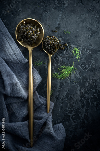 Black caviar in spoons on dark background. Natural sturgeon black caviar closeup. Delicatessen. Top view, flatlay