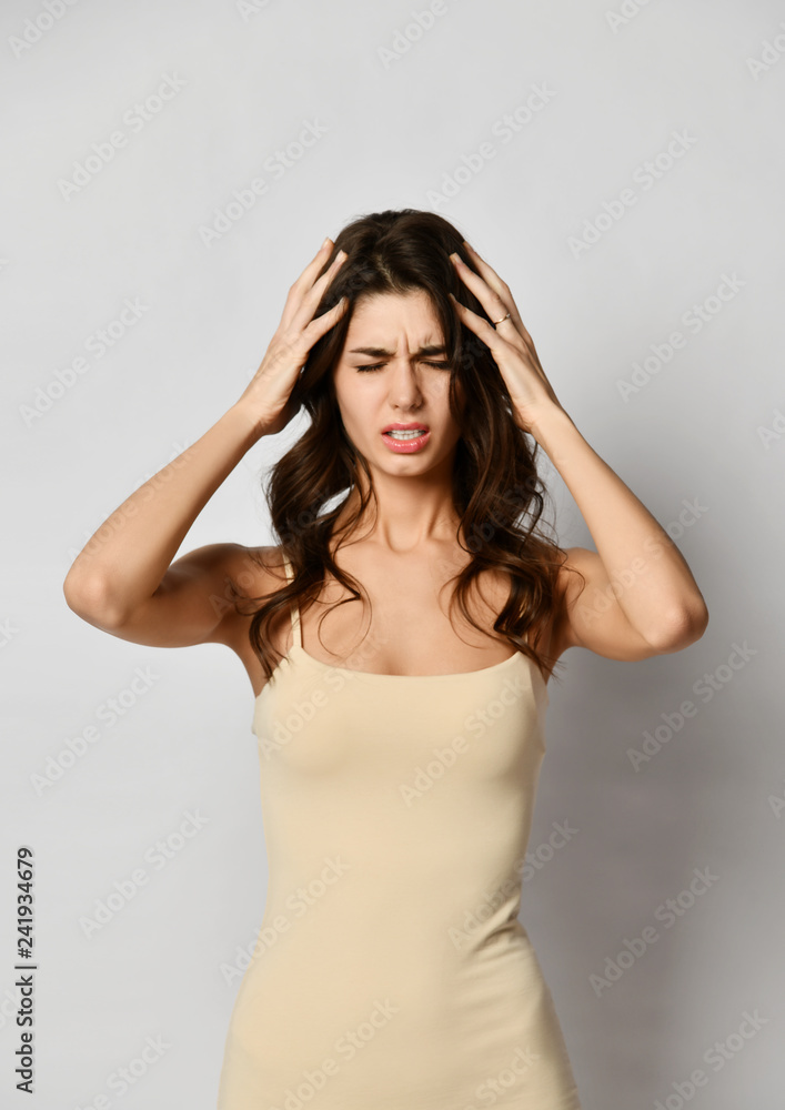 Portrait of young beautiful brunette woman touching her temples feeling stress suffering from headache Portrait of young beautiful brunette woman touching her temples feeling stress suffering from headache