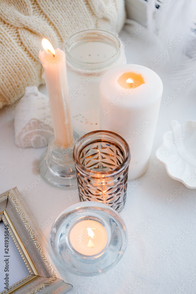Cosy cozy and soft winter spring white monochrome background, knitted pillow and candles on windowsill board. Christmas holidays, chill, calmness, relax at home Cosy cozy and soft winter spring white monochrome background, knitted pillow and candles on windowsill board. Christmas holidays, chill, calmness, relax at home
