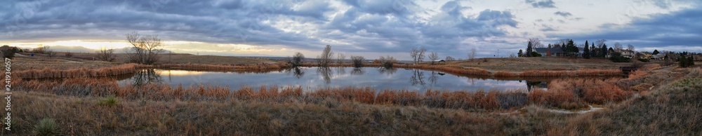 Views of Josh’s Pond walking path, Reflecting Sunset in Broomfield Colorado surrounded by Cattails, plains and Rocky mountain landscape during sunset. United States.