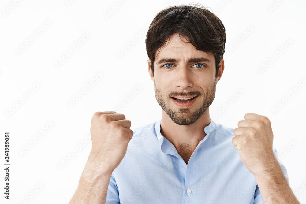 Close-up shot of confident and upbeat young creative handsome man with blue eyes and beard raising clenched fists in yes gesture being self-assured, triumphing celebrating successful deal Close-up shot of confident and upbeat young creative handsome man with blue eyes and beard raising clenched fists in yes gesture being self-assured, triumphing celebrating successful deal