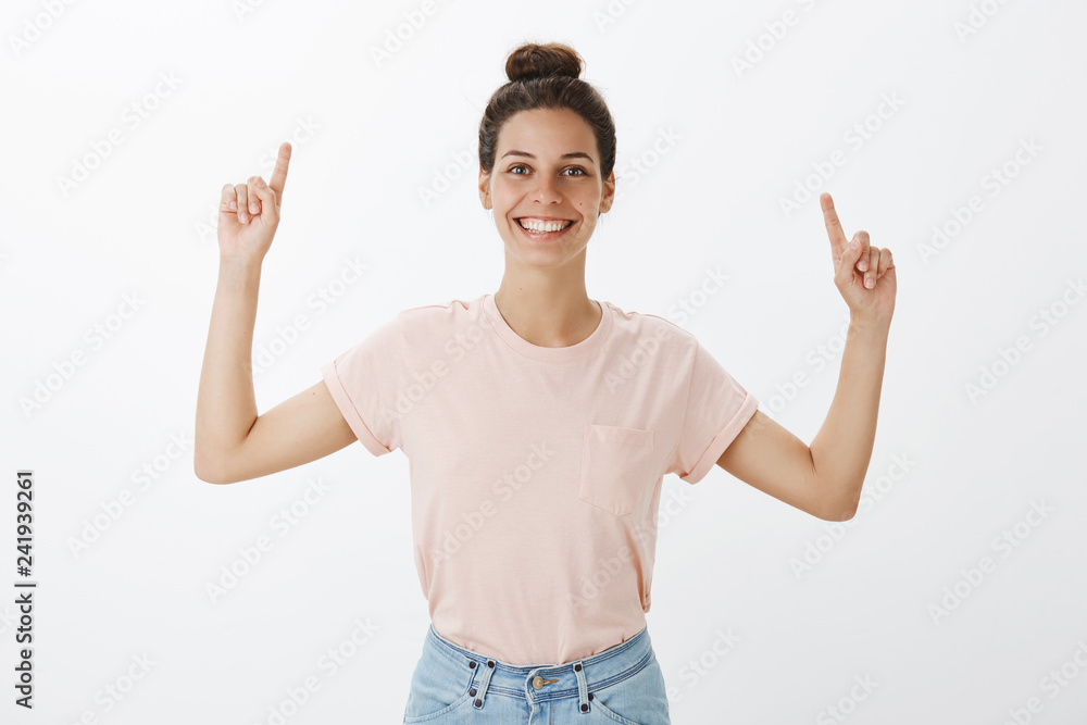 Proud and delighted optimistic good-looking female in casual outfit pointing up with raised arms smiling pleased and happy as wanting to show awesome thing to friend posing amused over gray background Proud and delighted optimistic good-looking female in casual outfit pointing up with raised arms smiling pleased and happy as wanting to show awesome thing to friend posing amused over gray background