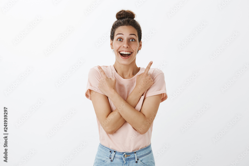 Obraz premium Portrait of delighted and impressed good-looking surprised woman pointing sideways as crossing arms on chest, showing right and left corner and reacting amused on great products on sale, smiling