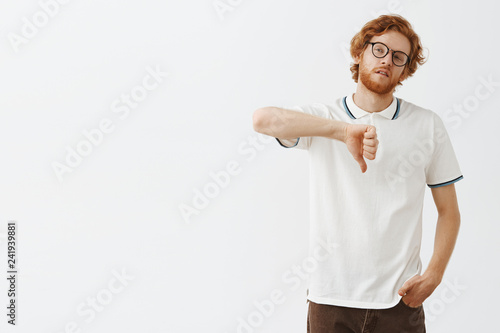 Foto Attractive redhead male snob in glasses and casual outfit tilting head looking l