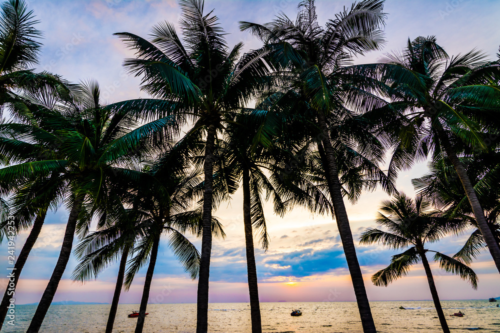 Obraz premium Beautiful colorful silhouette coconut palm trees on beach at sunset.