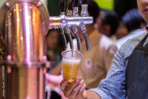 Barman or bartender pouring a beer from beer tap
