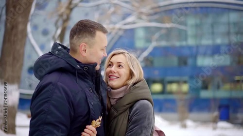 joyful adult spouses are hugging and kissing outdoors in cold winter day, kidding and rejoicing photo