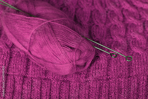 Knit. Knitted pattern and a skein of wool yarn with knitting on it. Purple color.