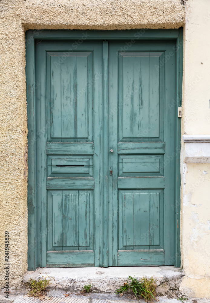 Wooden worn green door, closed. Traditional house facade, old town of Plaka, Athens Greece