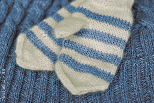 Knit. Homemade knitted striped mittens on knitted pattern background. Blue colour.
