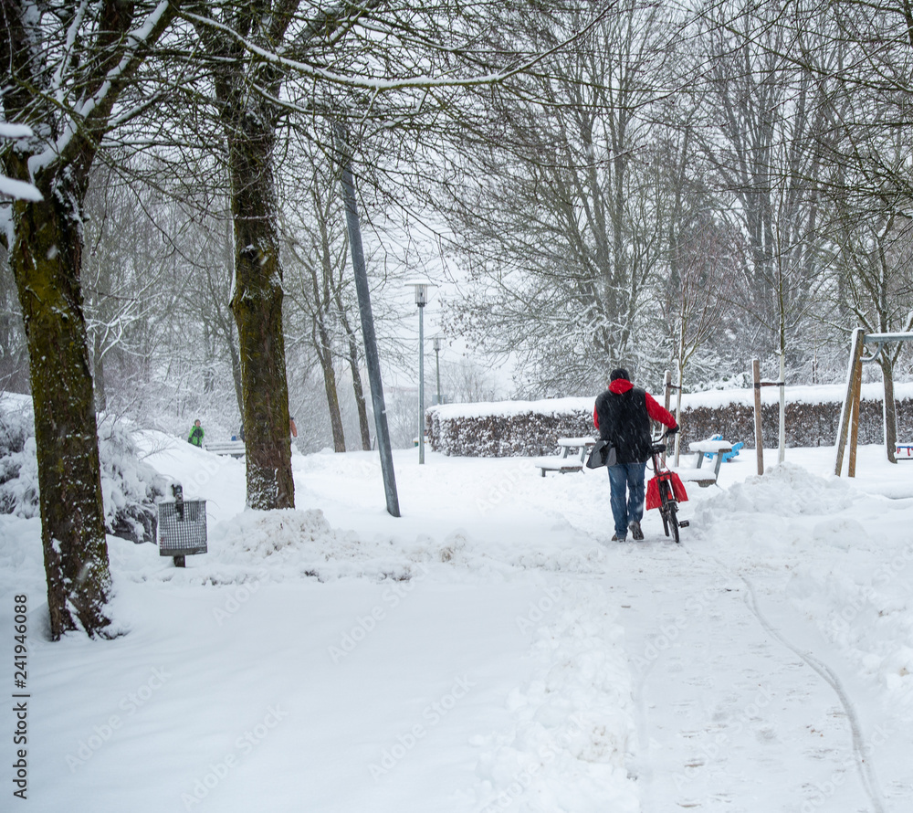 Man pushing his bicycle in snow