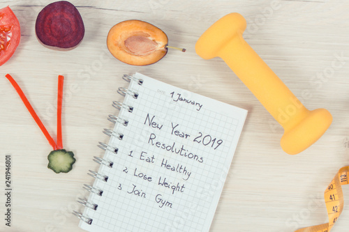 New year resolutions for 2019 and clock made of fresh fruits with vegetables, dumbbell and centimeter