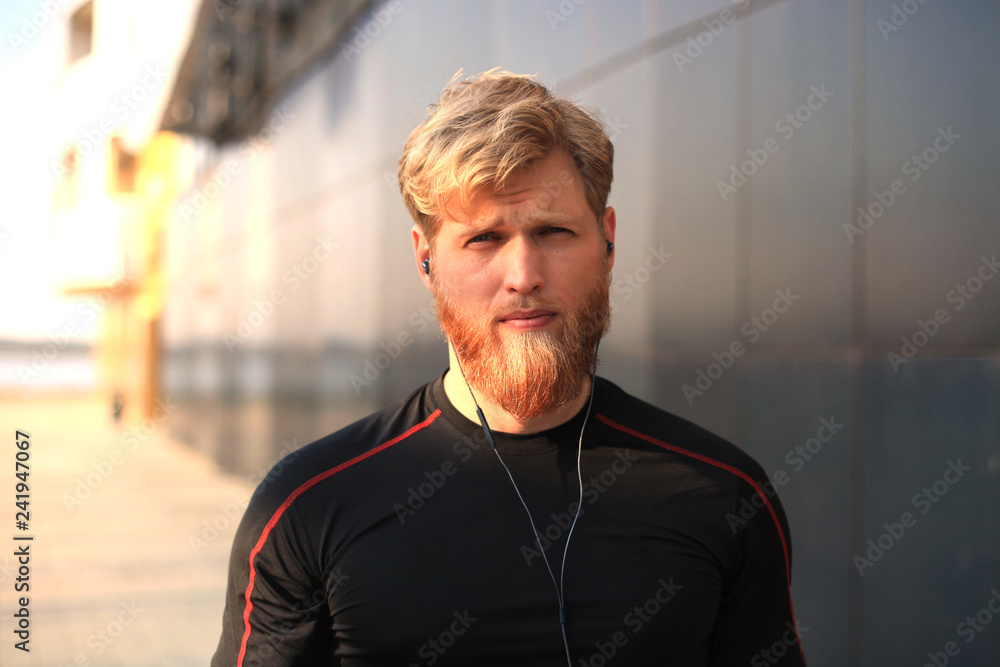 confident sporty young man looking at camera while standing outside, at sunset or sunrise. Runner. confident sporty young man looking at camera while standing outside, at sunset or sunrise. Runner.