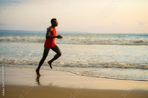 young attractive fit athletic and strong black African American man running at the beach training hard and sprinting on sea water in professional athlete lifestyle