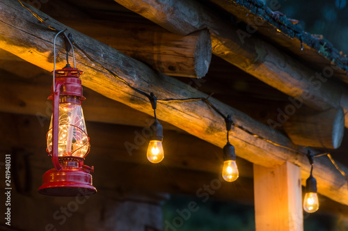 Fotografía Red metal storm lantern hung outside rustic log cabin.