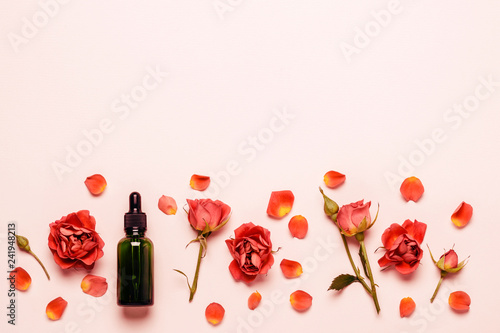 Delicate pink background with roses, petals and essential oil