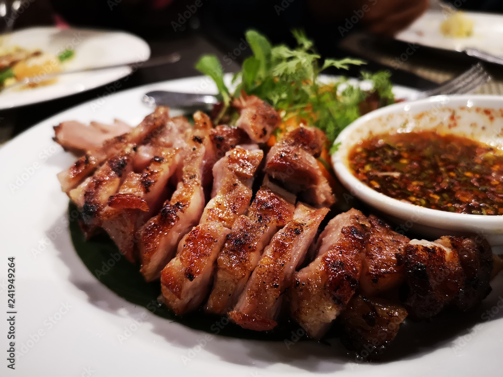 tasty slice grilled pork on white dish in Thai restaurant