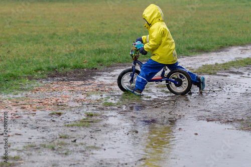 child riding a balance bicycle in rain