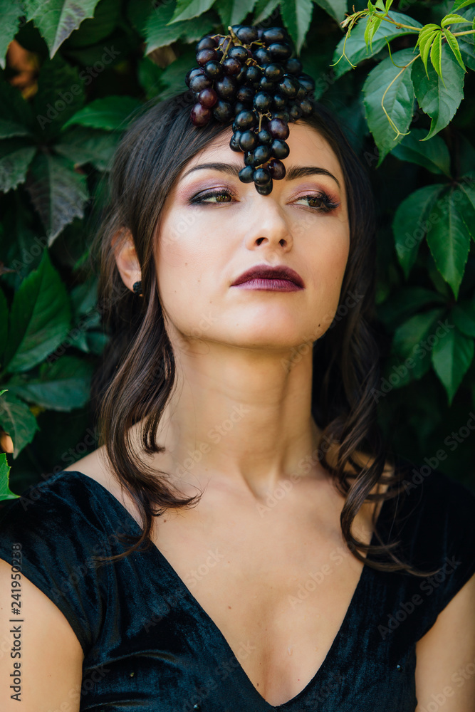 Portrait of young sexy brunette with black grapes on head. Portrait of young sexy brunette with black grapes on head.