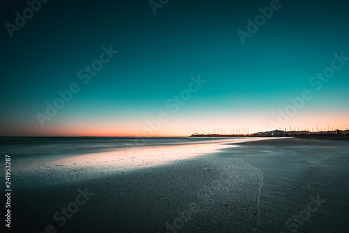 Teal and orange view of winter beach sunset and sea, with copy space available
