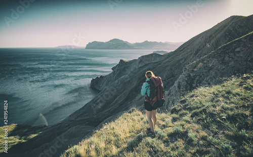 Girl hiker on a the edge above the sea