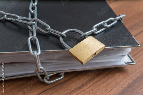 Confidential files and documents in binder locked with padlock and chain.