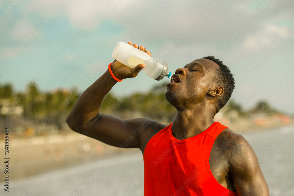 Young fitness black man holding a water bottle impressed holding copy space  on palm. Stock Photo