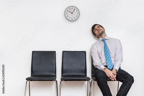 Tired and exhausted man is sitting in waiting room on chair. photo