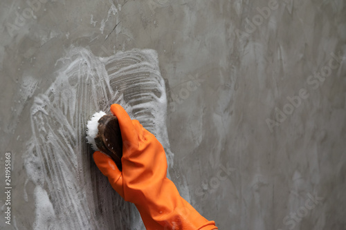 Принти на полотні Woman's hand wearing orange rubber gloves is used to convert scrub cleaning on the concrete wall