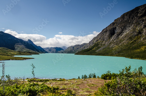 Amazing view of the crystal blue lake Gjende in Jotunheimen National Park with beautiful mountains behind and blue sky