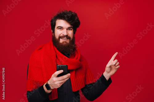 Photo of smiling bearded man hollding phone and pointing away © Vulp