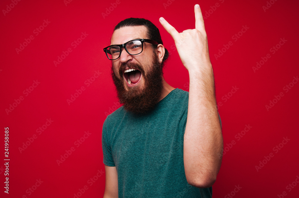 Naklejka premium Photo of screaming bearded man gesturing, rock symbol