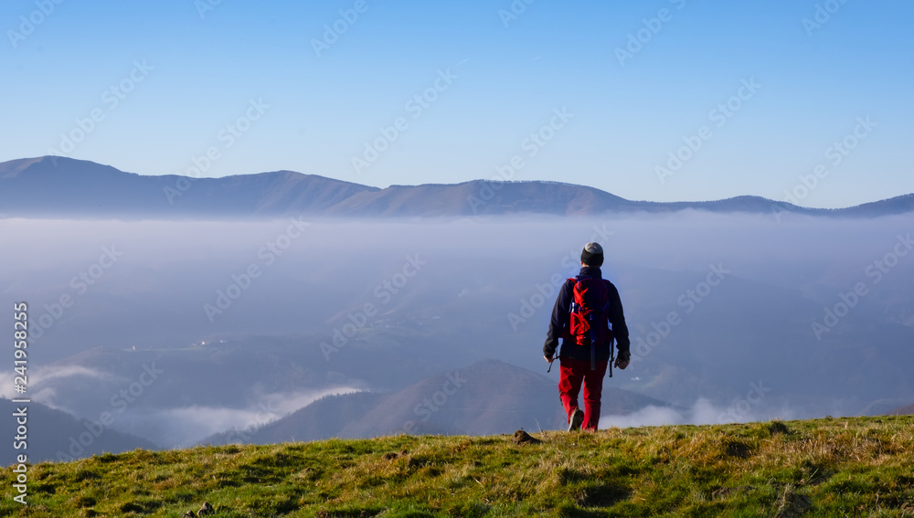 Man Traveler on mountain summit enjoying aerial view over clouds in Aiako Harriak Natural Park, Basque Country.