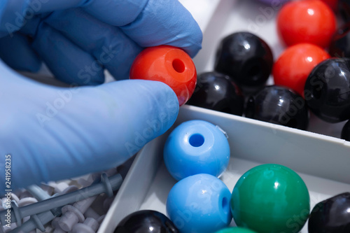 Person wearing gloves taking an oxygen molecule from a molecular model kit