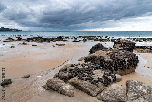 The wet sand and mussel-covered rocks are visible at low tide on a beach in northern Brittany