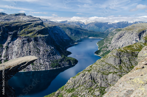 Spectacular view of Trolltunga rock with a blue lake 700 meters lower and interesting sky with few clouds