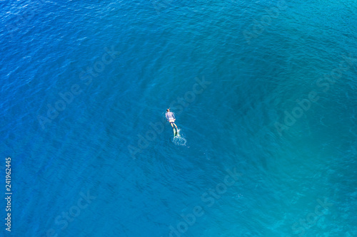 Aerial drone view of a snorkeler over a tropical coral reef