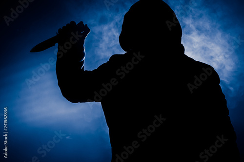 Foto A dangerous hooded man standing in the dark and holding a knife