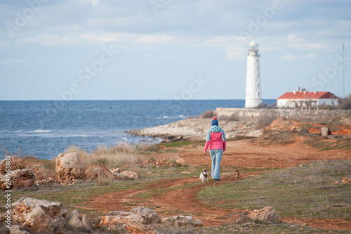 sport young woman wearing spring track suit walking along shore with dogs © ruslanshug