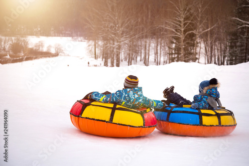 children are rolling down snow tubing